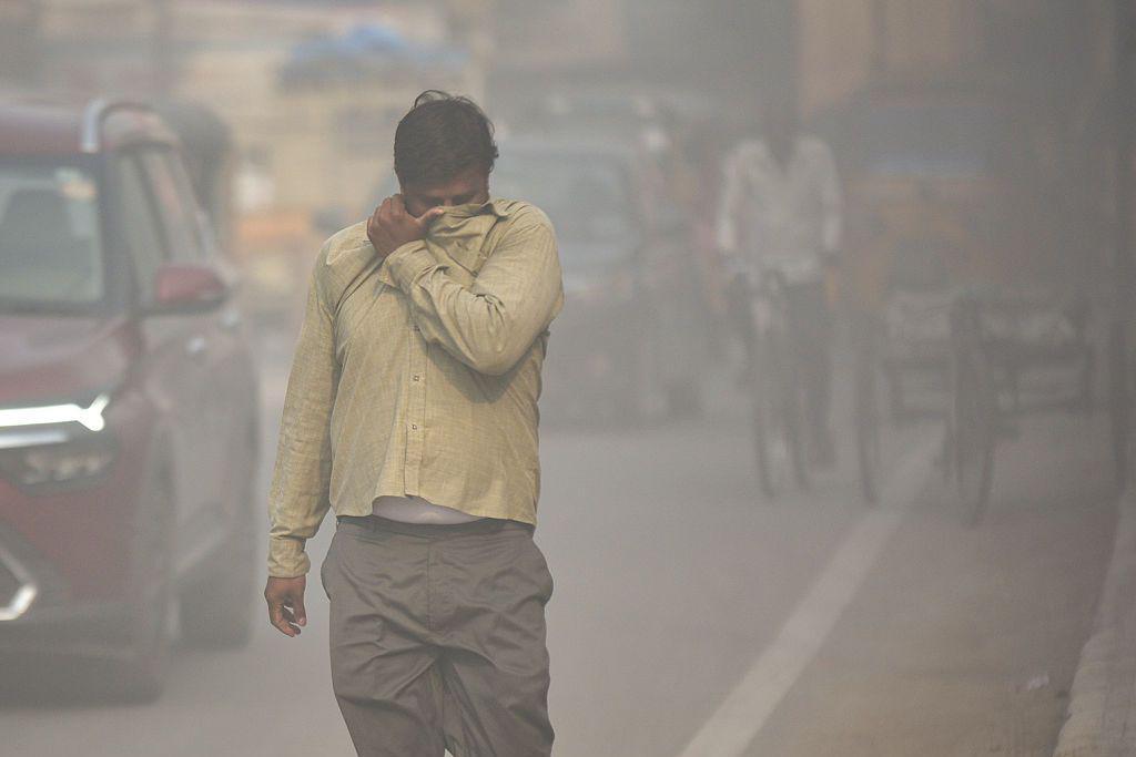 A pedestrian on a road through a haze of dust pollution from a nearby construction site in Hyderabad