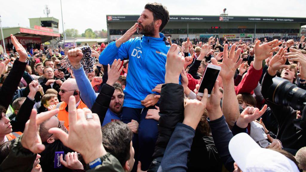 Danny Cowley blows a kiss to the stands as he is held aloft by Lincoln fans