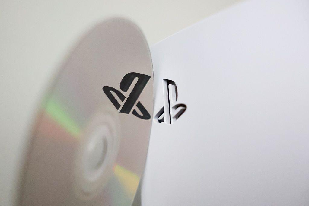 A playstation disc next to the PS5 console reflects the logo.