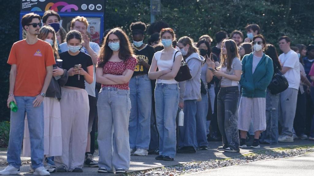 Students queue up for vaccine outside - many are wearing face masks