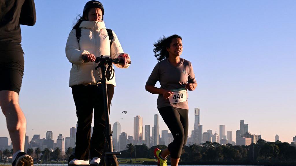 Woman rides on an electric scooter near Albert Park Lake in Melbourne