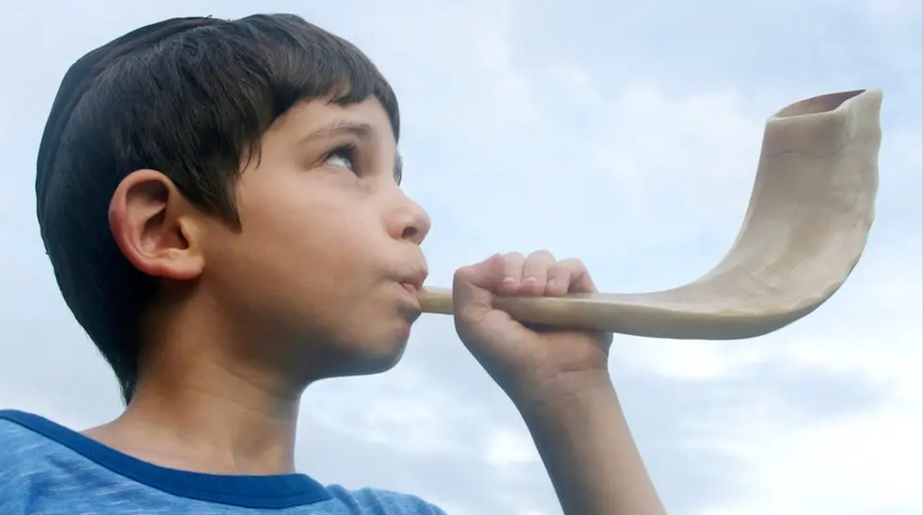 Boy blowing a Shofar instrument