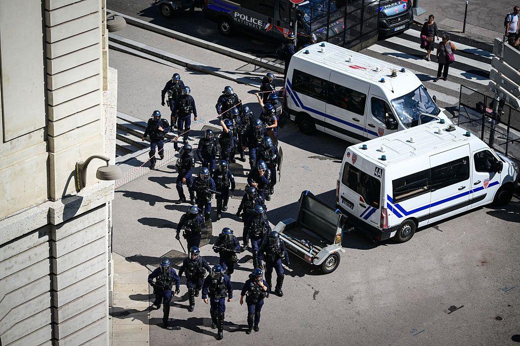 A number of  police officers in riot gear photographed from abroad near to two police vans