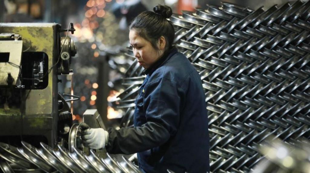 A woman works with steel bike rims for export at a factory in Hangzhou in east China's Zhejiang province Thursday, Feb. 20, 2025