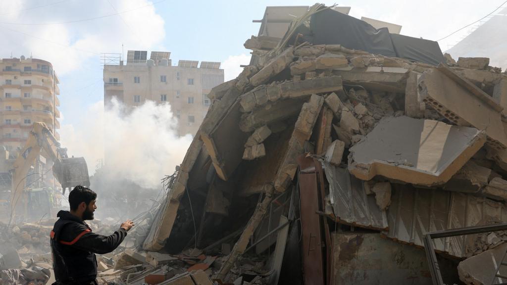 A rescuer stands next to a pile of rubble at the site of an Israeli strike in Tyre, Lebanon, April 8, 2026.