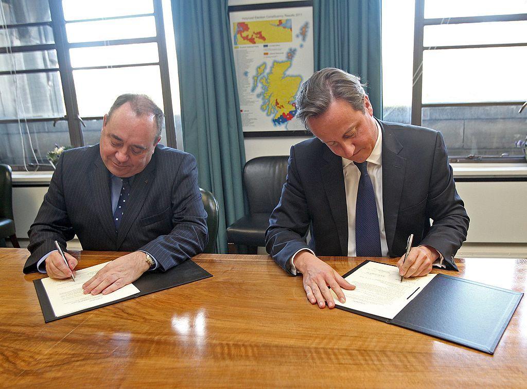 Alex Salmond on the left and David Cameron on the right signing identical copies of the Edinburgh Agreement at a polished wooden table