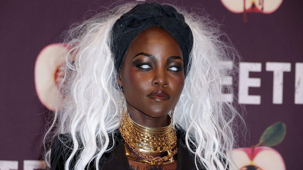 Lupita Nyong'o wearing a bright white wig and white contact lenses.