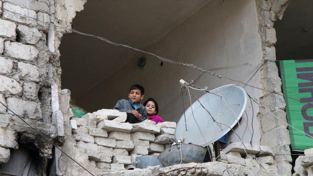 Children look out from a destroyed home in Aleppo, Syria