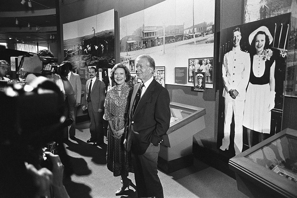 Jimmy and Rosalynn Carter give a tour of the Carter Presidential Center in1986, and pose in front of a photo from their wedding day.