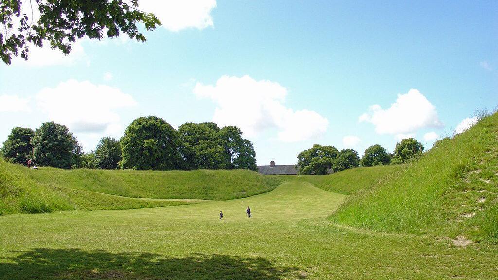 Maumbury Rings earthworks - a large grass bowl-shaped area surrounded by trees