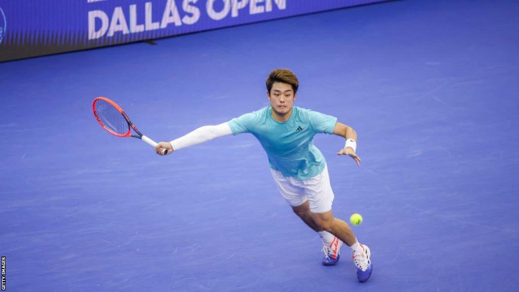 Wu Yibing stretches to his right to hit a forehand return