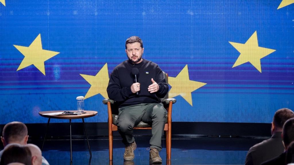 Zelensky speaks on stage in front of an EU flag