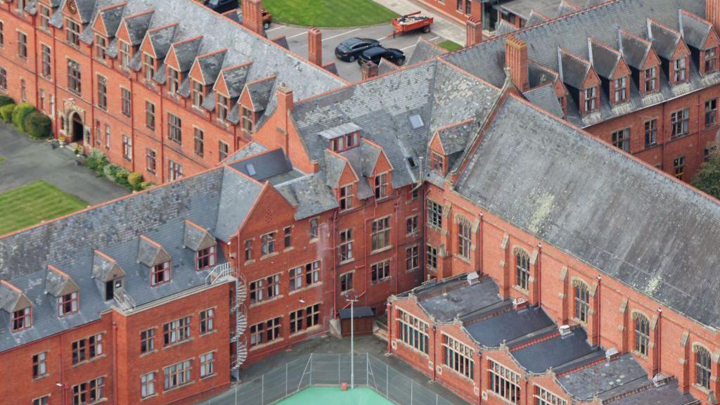 An aerial view of Ellesmere College showing various multi-storey red-brick buildings with a grey roof