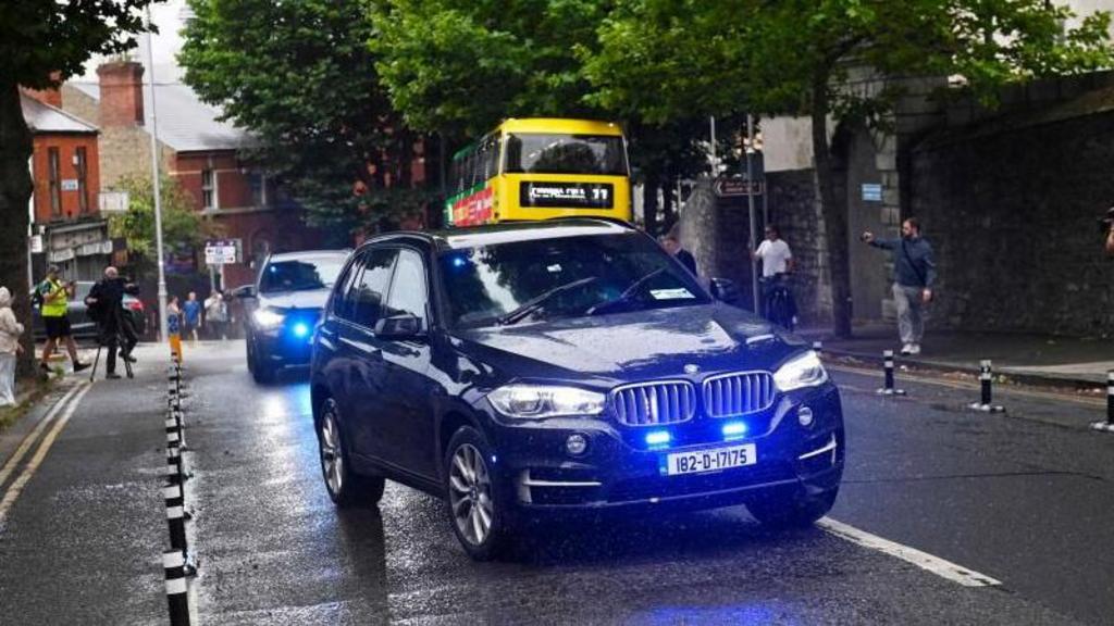 A convoy of police vehicles is shown arriving at court in Dublin, with blue lights flashing.