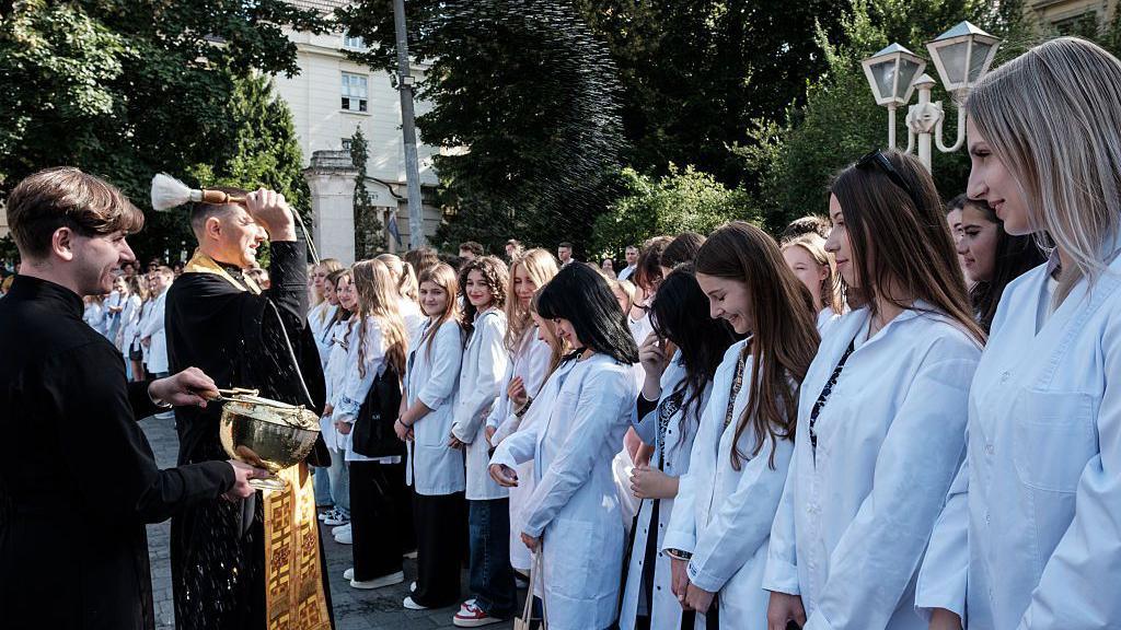 A priest sprays new students with holy water at the start of the new university year in Kyiv