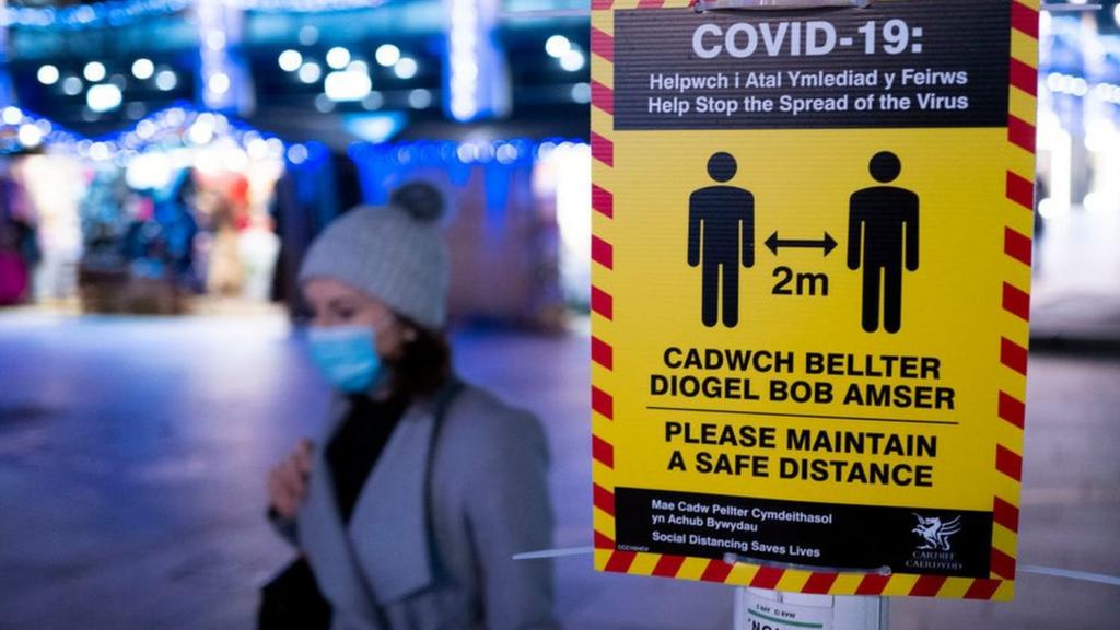 Woman walking by social distancing sign