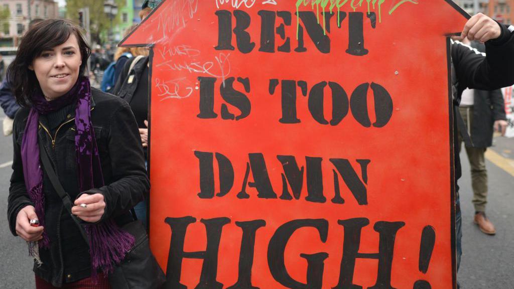 A protester seen with 'The Rent Is Too Damn High!' sign during a protest against the housing crisis 'Raise the Roof'; On Saturday, May 18, 2019, in Dublin, Ireland.