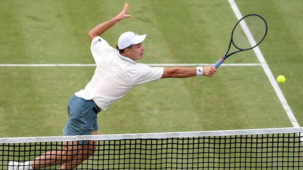 Arthur Fery stretches to play a backhand volley