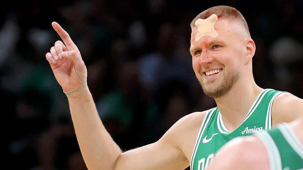 Kristaps Porzingis smiles as he returns to the court with a bandage on his forehead