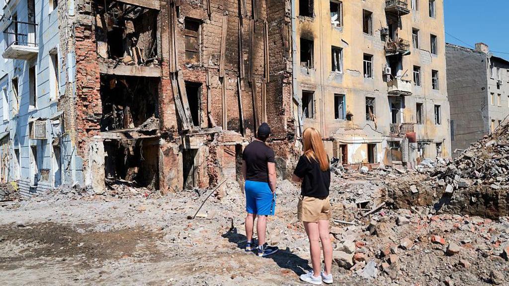 Residents step out of their car to take in the devastation of residential buildings bombed by Russian forces on August 10, 2025 in Kramatorsk, Ukraine