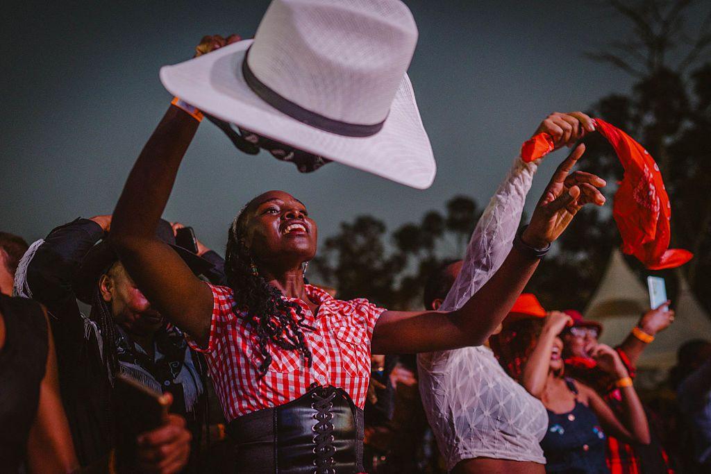  Revellers line dance during the International Cowboy Day at Ngong race course. They wave cowboy hats and bandannas in the air.