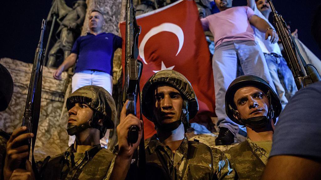 Turkish solders stand with guns at Taksim square as people react in Istanbul on July 16, 2016. 