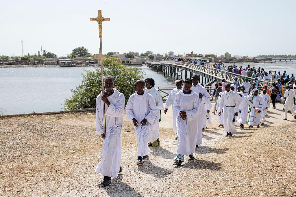 An altar boy in white carries a cross as he leads the procession to the cemetery on the island of Fadiouth - Saturday 1 November 2025.