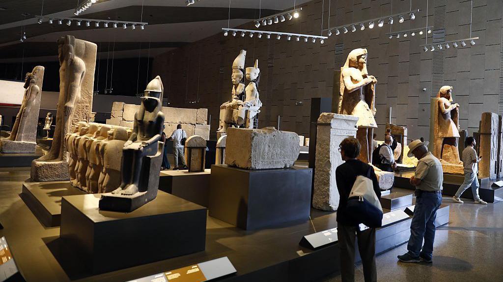 Inside of the museum with visitors seen walking around looking a lots of statues from the time of Ancient Egypt.