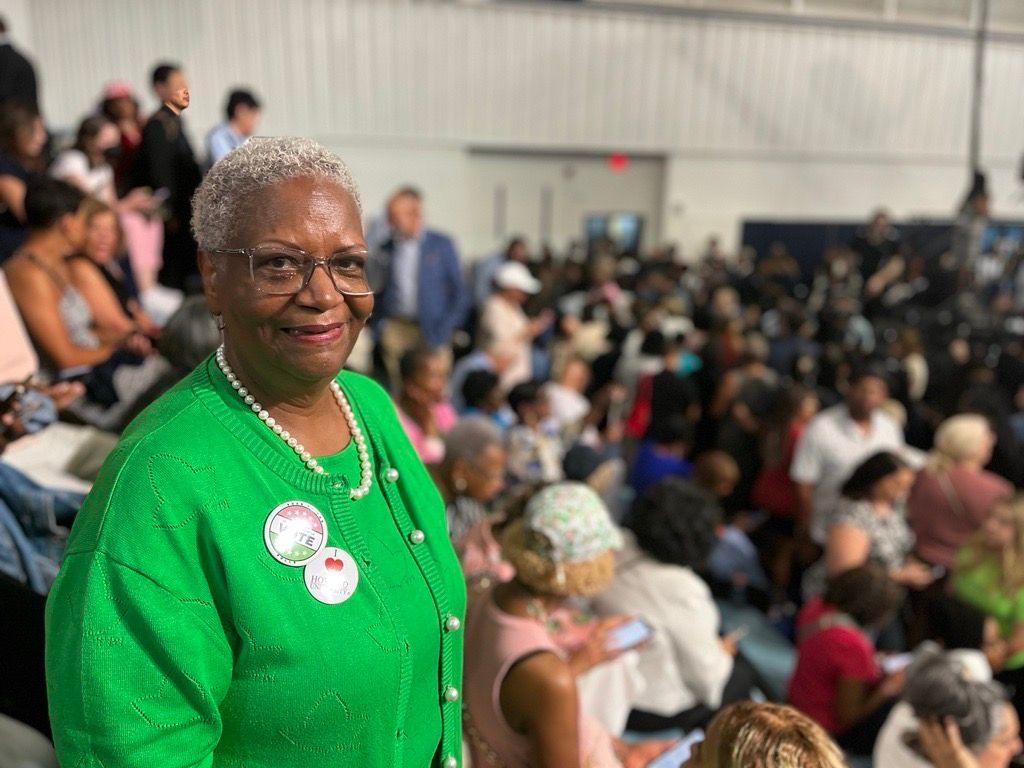 Woman stands in green sweater at Biden rally