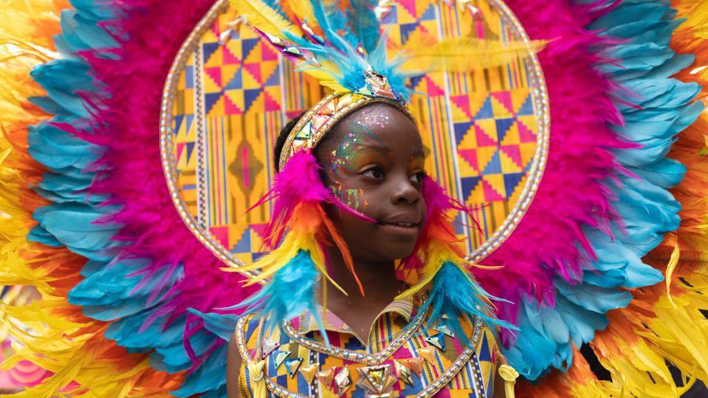 Child in colourful outfit at carnival. 