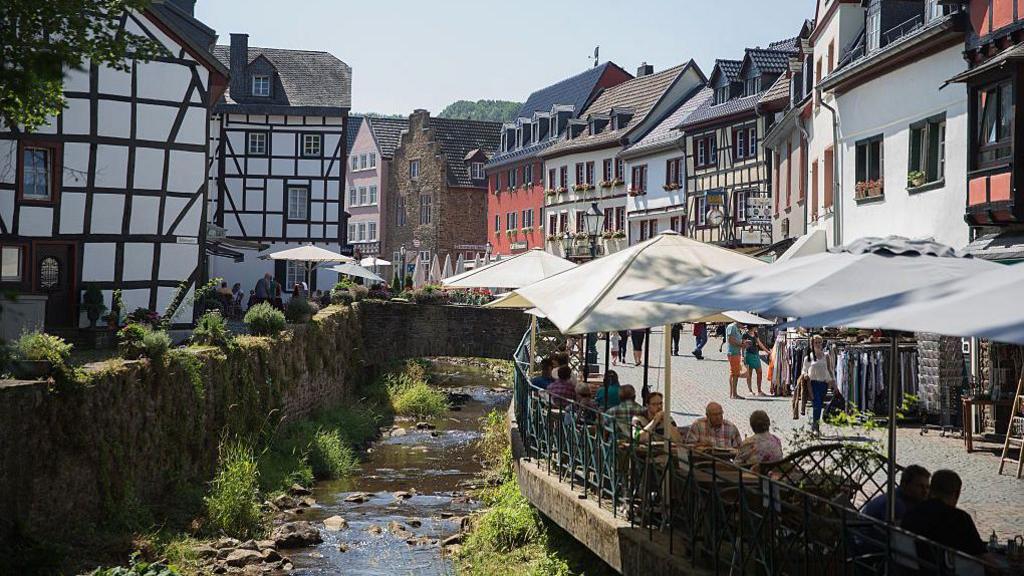 A picture of a river running through Bad Münstereifel in Germany with traditional German buildings along either side. 