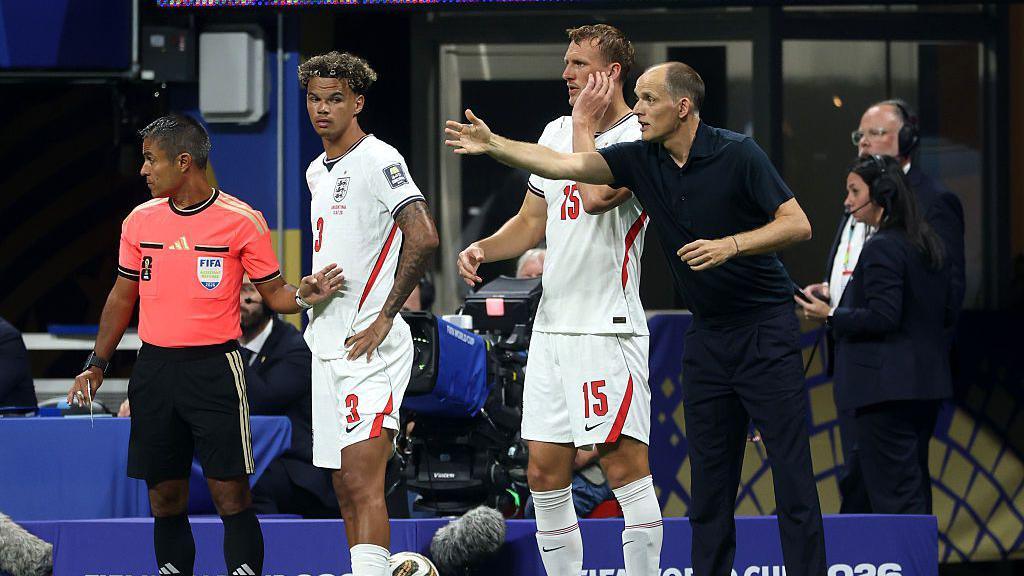Nico O'Reilly #3 and Dan Burn #15 of England stand on the touchline while Thomas Tuchel shouts instructions at his team