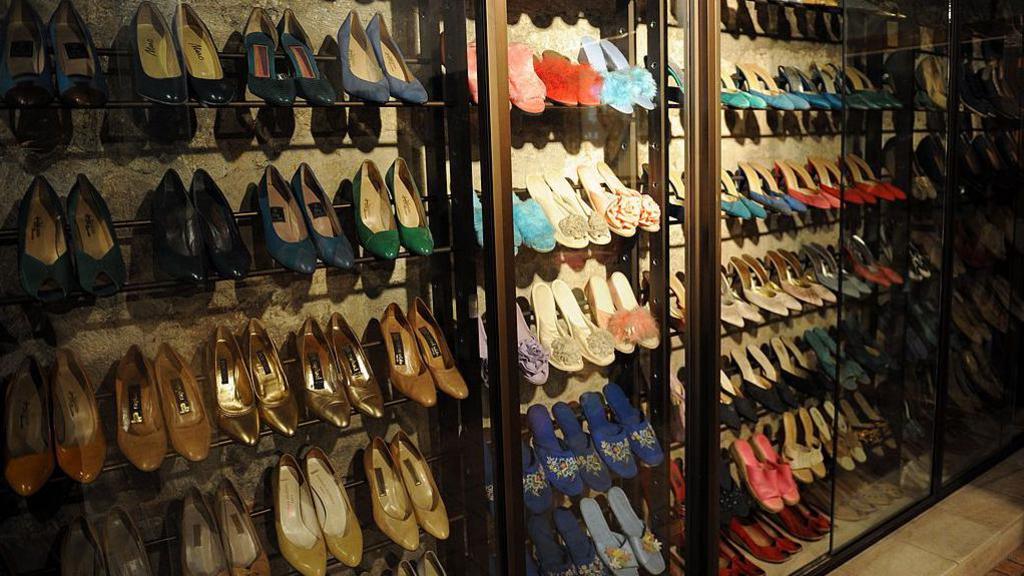 Rows of colourful high heeled shoes being displayed behind clear glass cabinets