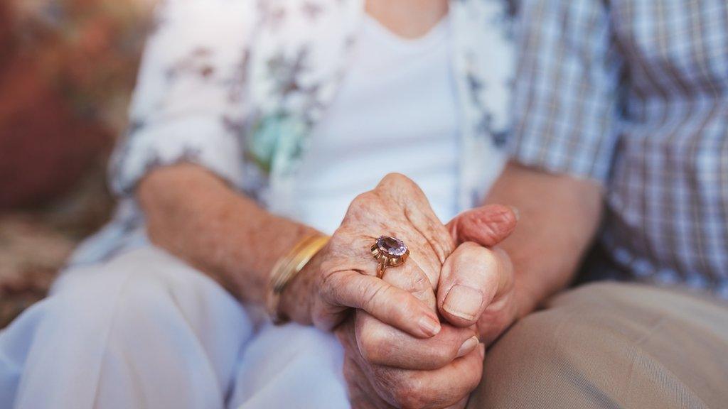 Elderly couple holding hands