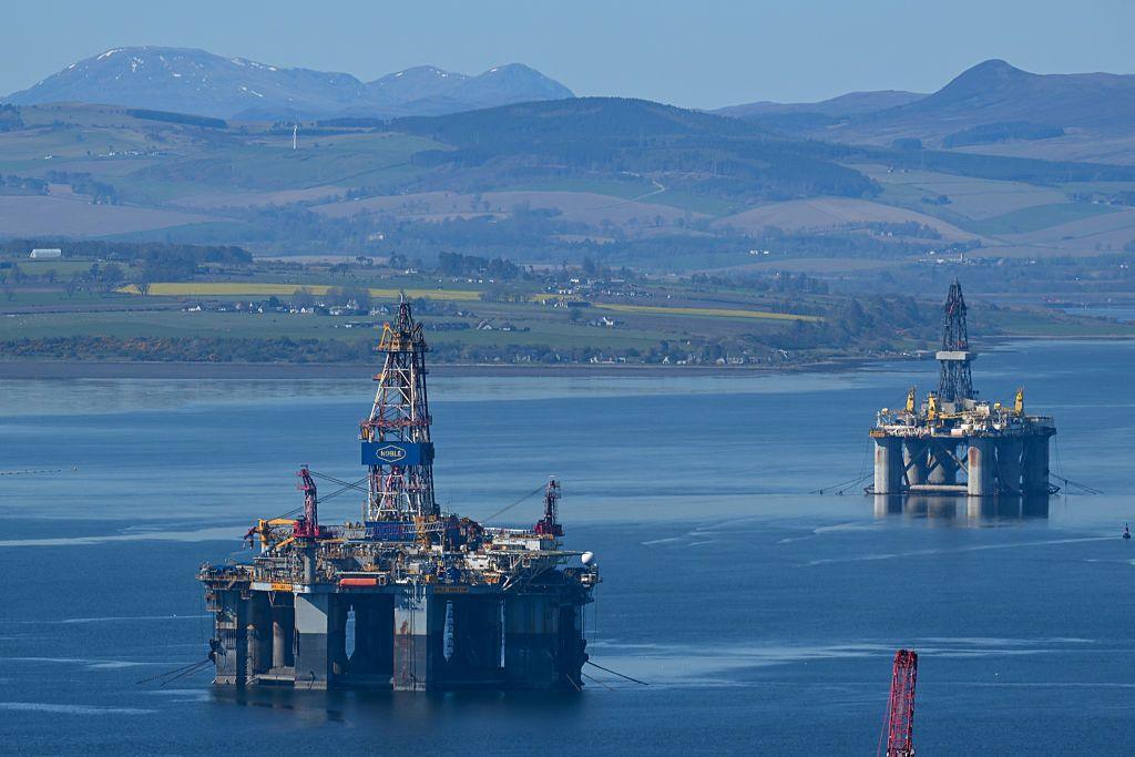 Two oil platforms on the Cromarty Firth - a clear blue stretch of water with hills and snow-capped mountains in the background