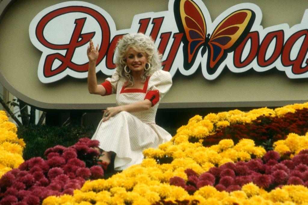 Dolly Parton poses for a picture in front of the Dollywood sign.