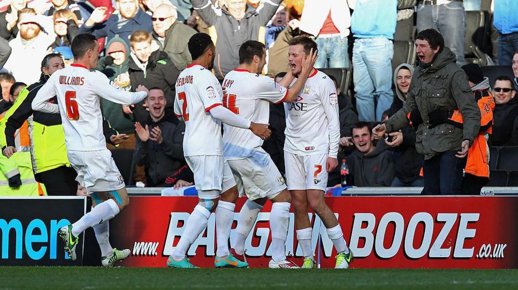 MK Dons players celebrate scoring against AFC Wimbledon