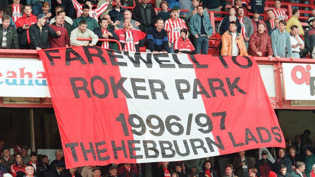 A large red and white flag hanging from one of the stands at Roker Park during Sunderland's final home game in May 1977. It reads: "Farewell to Roker Park, 1996/97, The Hebburn lads."