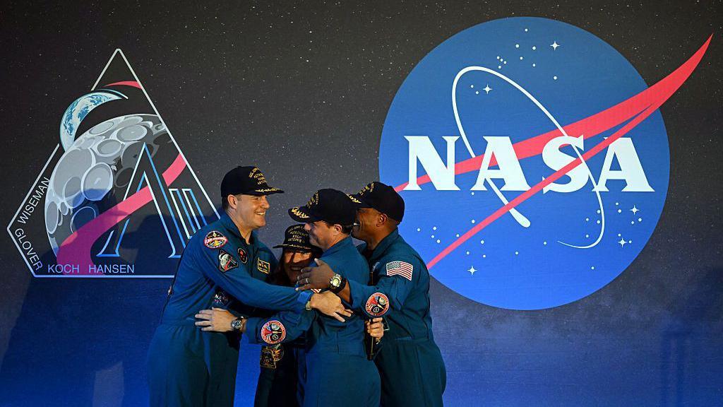 Four Artemis II astronauts hugging.