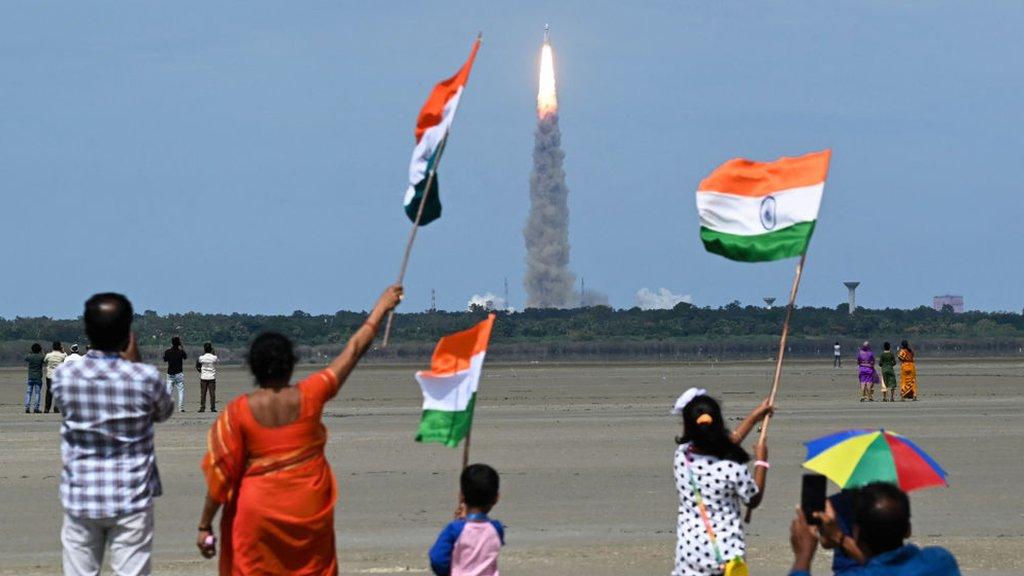 Children waving Indian flags as rocket launches in background