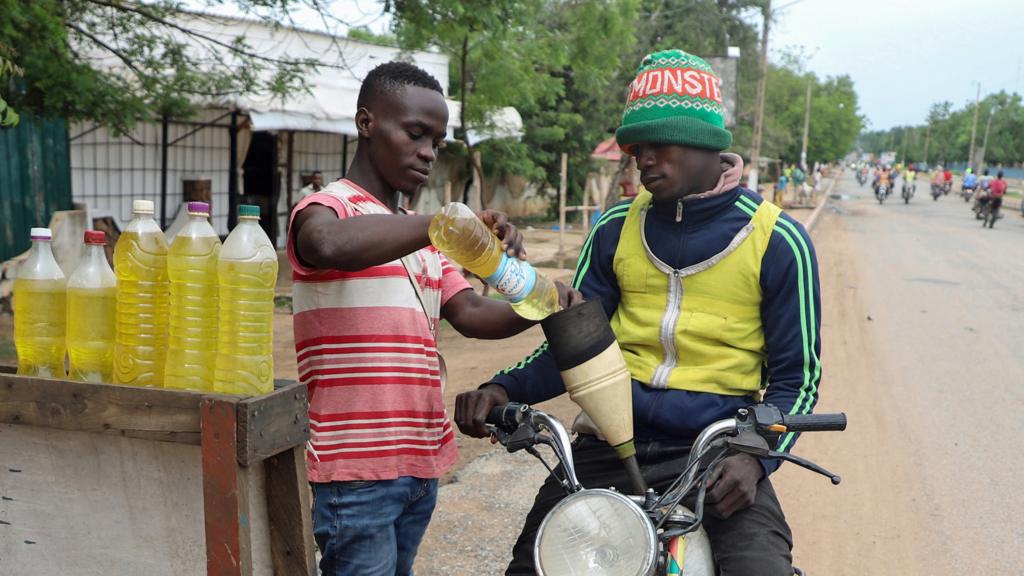 A motorcycle taxi man gets his bike refuelled with smuggled Nigerian fuel in Garoua, Cameroon - June 2023