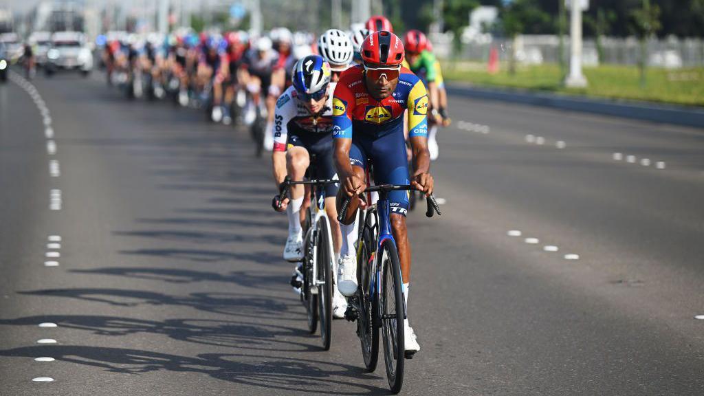 Cyclists in professional kit ride on the road in a vertical line in Abu Dhabi - Saturday 22 February 2025.