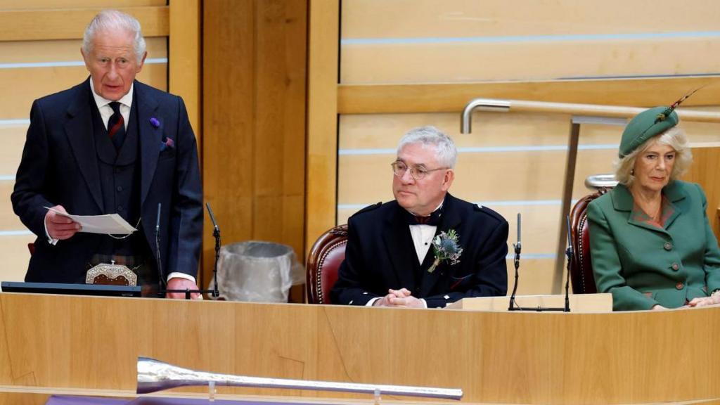 King Charles addresses Scottish parliament besides Presiding Officer and Queen Camilla 