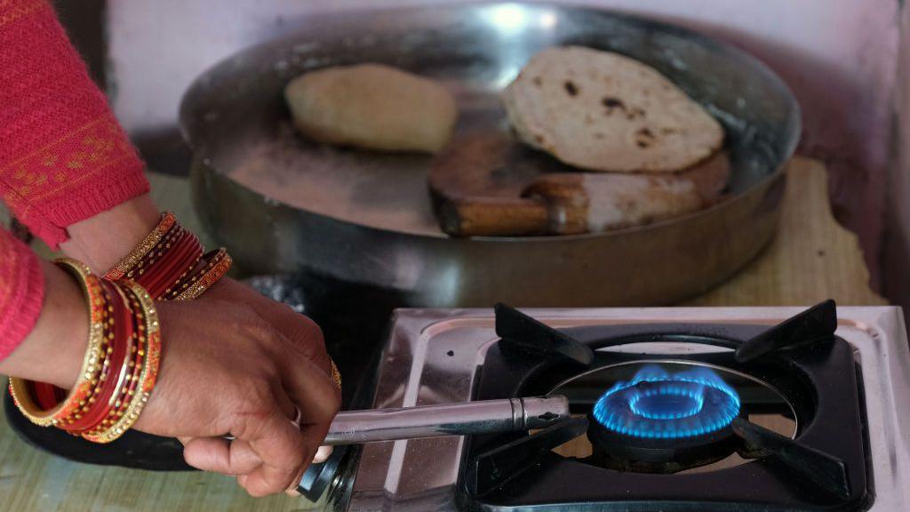 A woman lights a stove connected to an Indian Oil Corp. Indane brand liquefied petroleum gas (LPG) cylinder at a village home in Greater Noida, Uttar Pradesh, India, on Monday, Feb. 22, 2021. Photographer: T. Narayan/Bloomberg via Getty Images