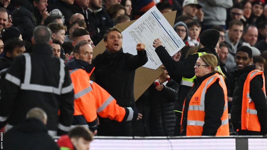 A supporter holds a sign in protest against manager Nathan Jones