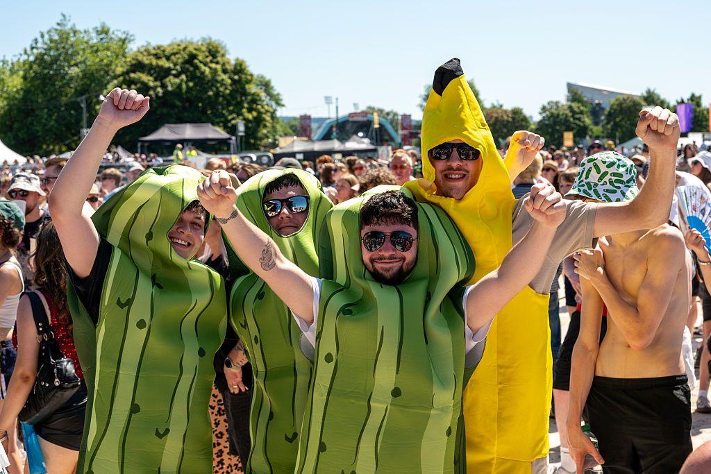 Four men smiling in costumes. Three men dressed as pickled gherkins and another man dressed as a banana.