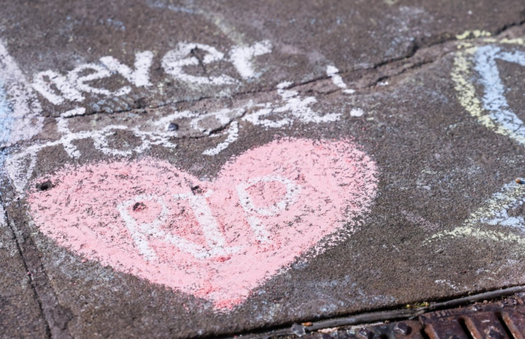 A pink chalk drawing of a heart with RIP written in the middle of it