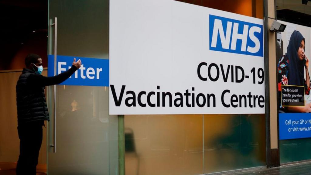 Man beckons people into the vaccination centre