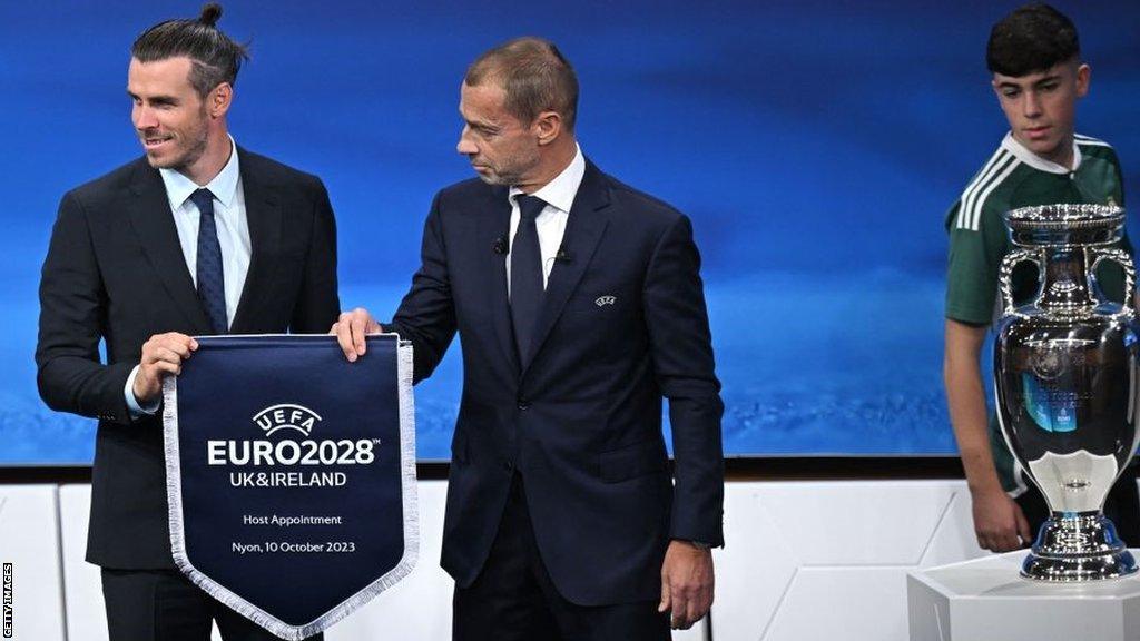 Chris Atherton has a glance at the European Championship trophy as Gareth Bale and Uefa president Aleksander Ceferin pose for photographs during the announcement of the successful UK and Ireland bid for Euro 2028