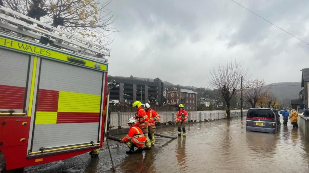 Firefighters pumping water from a street by the River Taff, in Pontypridd, Wales, following flooding